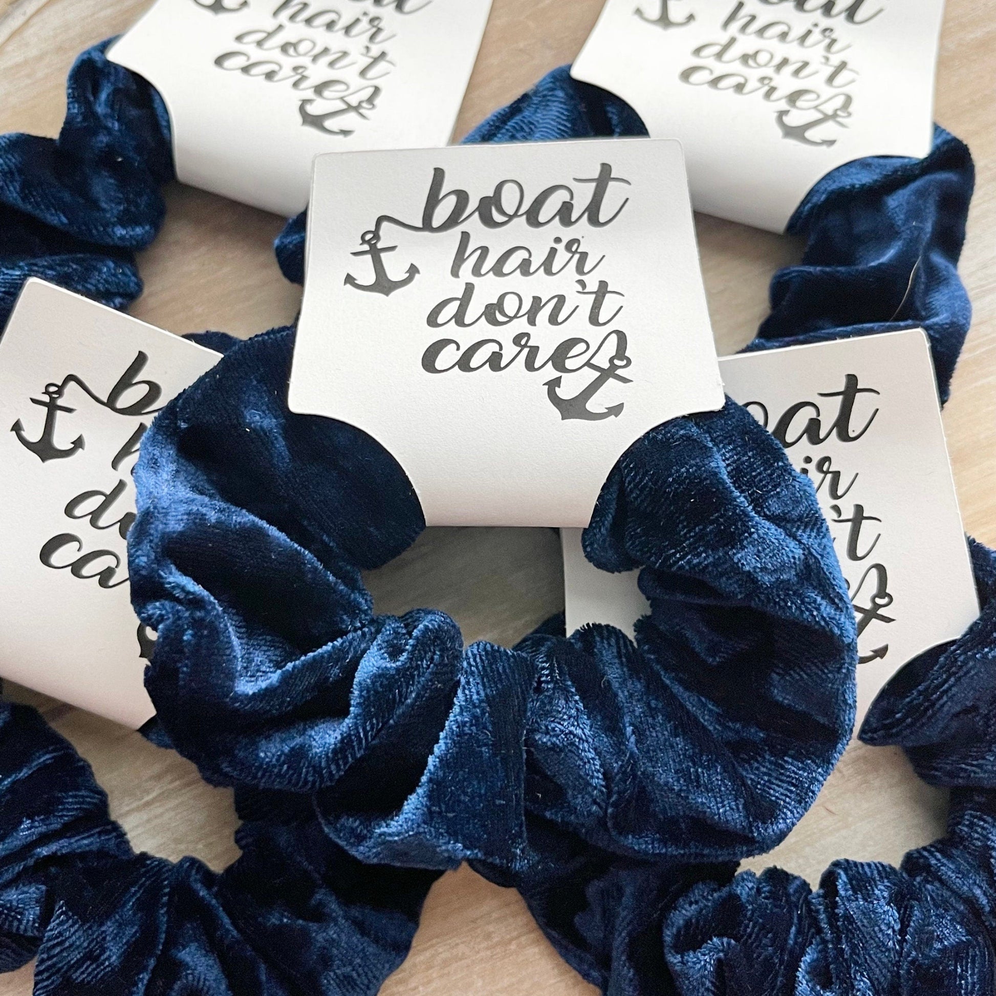 Blue scrunchies with 'boat hair don't care' text on a wooden surface