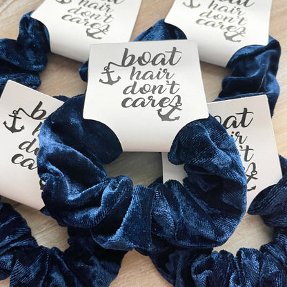 Blue scrunchies with 'boat hair don't care' text on a wooden surface