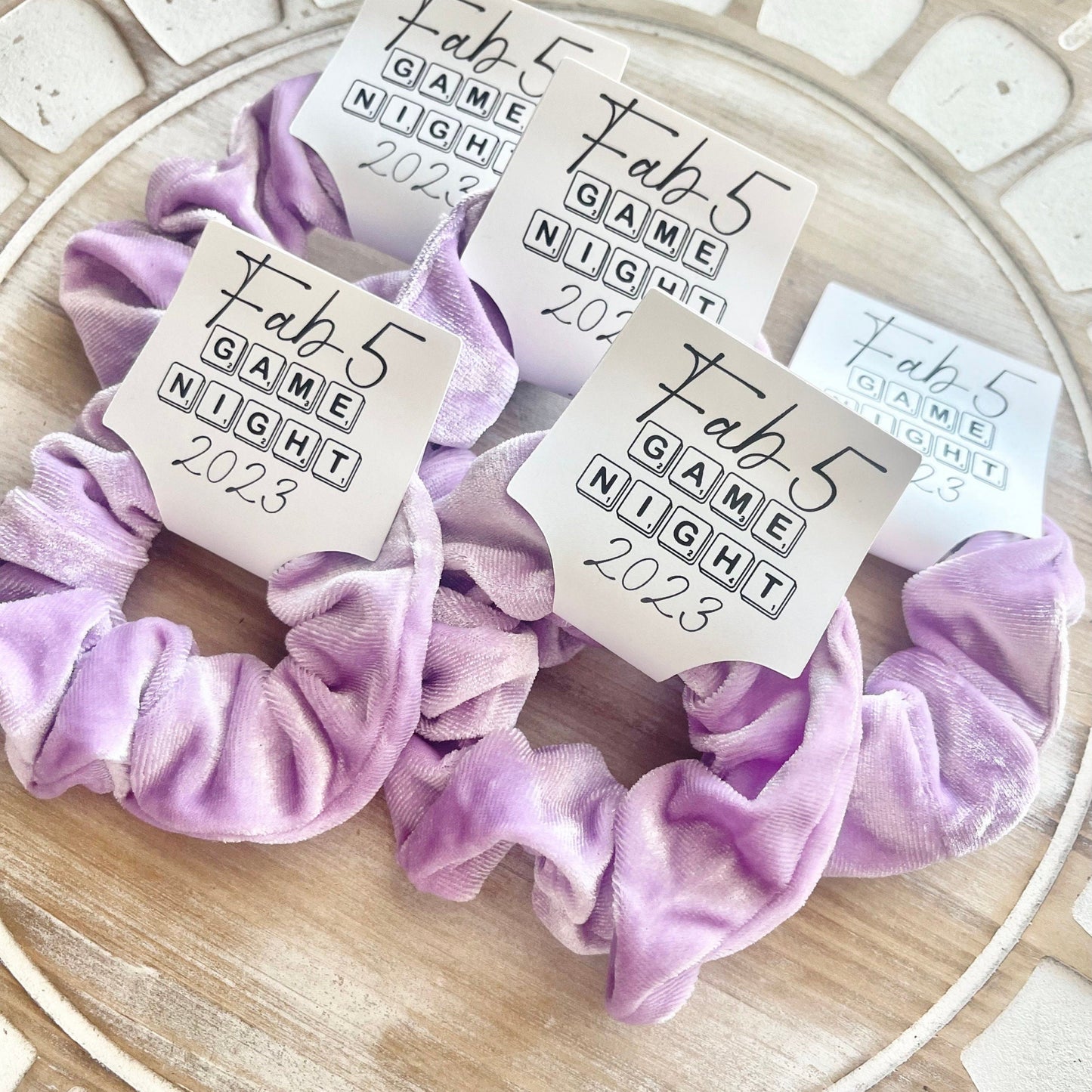 Purple scrunchies with 'Tab 5 Game Night 2023' labels on a decorative plate.