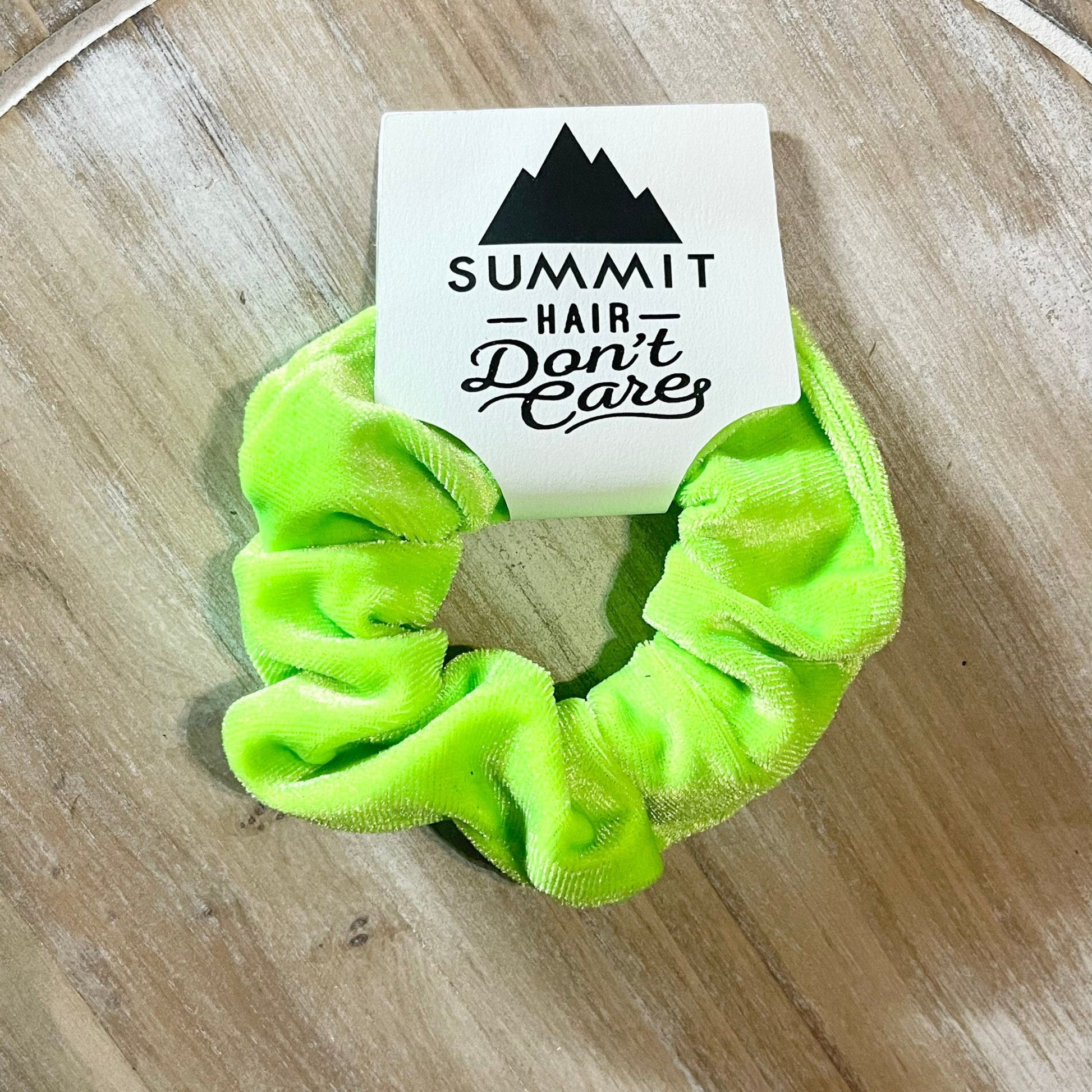 Neon green scrunchie with a Summit Hair Don't Care label on a wooden surface