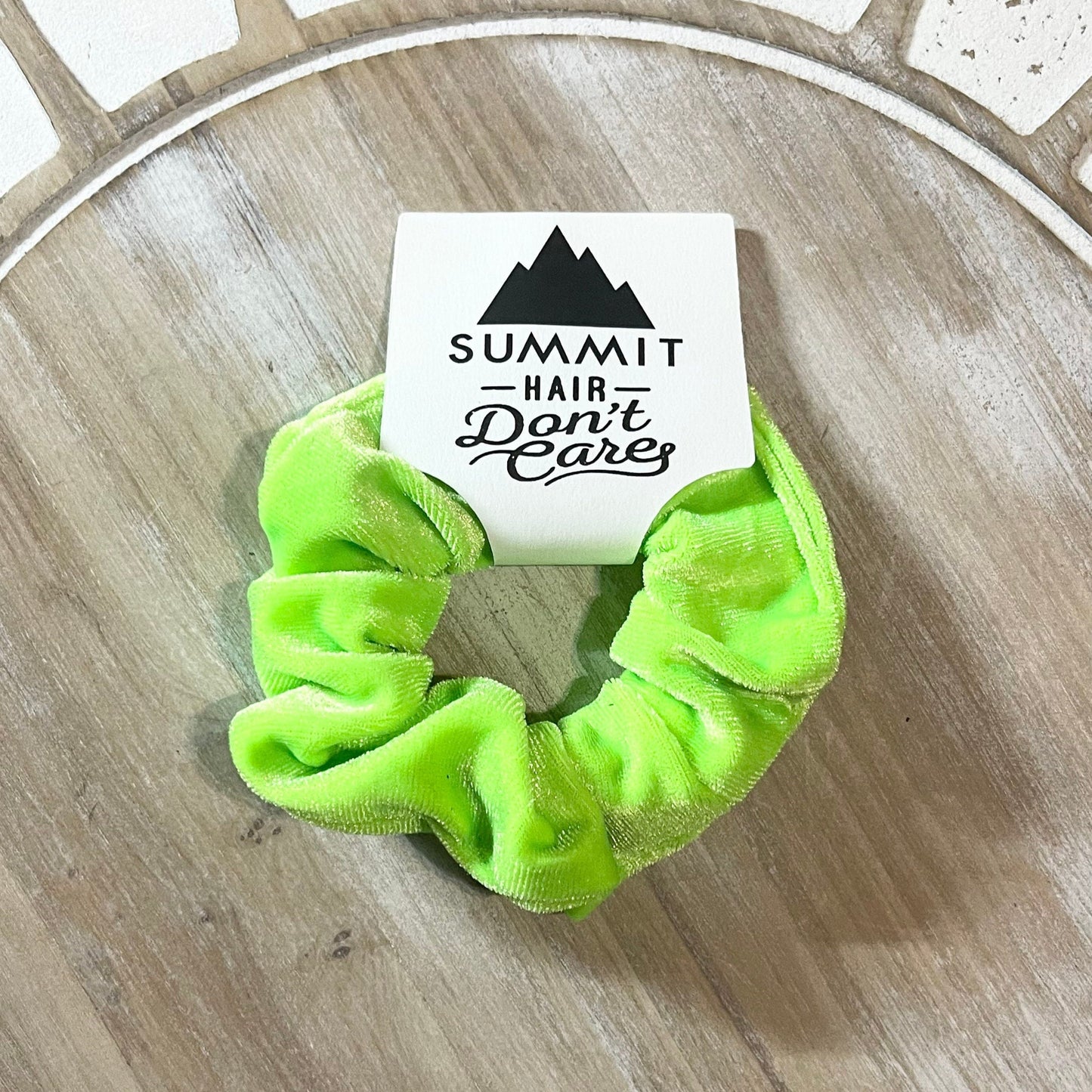 Green scrunchie with a card labeled 'Summit Hair Don't Care' on a wooden surface