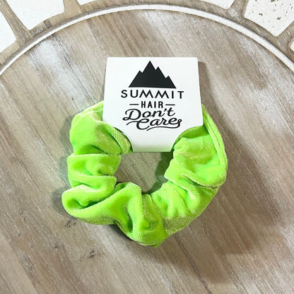 Green scrunchie with a card labeled 'Summit Hair Don't Care' on a wooden surface