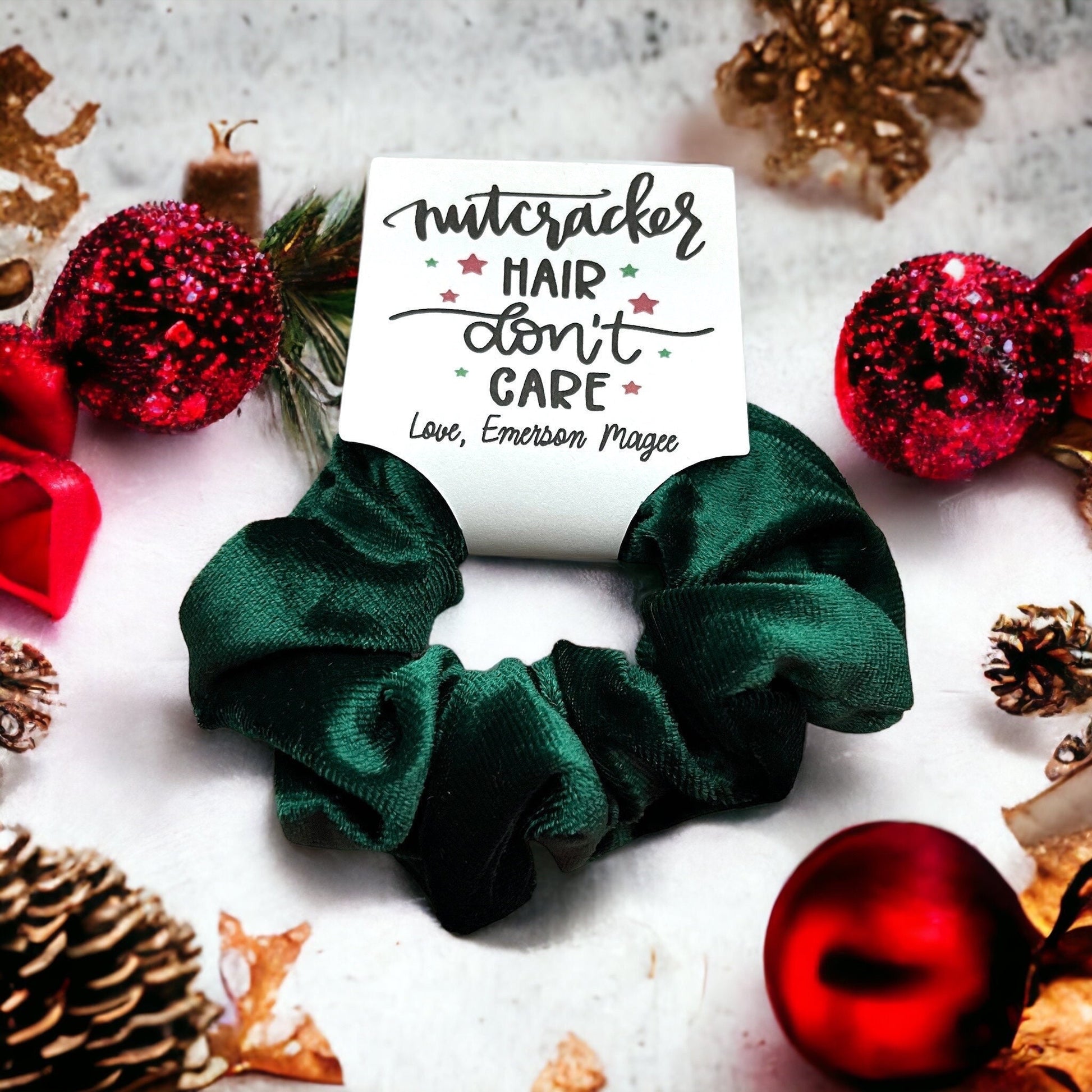 Green scrunchie with a card reading 'Nutcracker Hair Don't Care' surrounded by Christmas decorations on a light background.