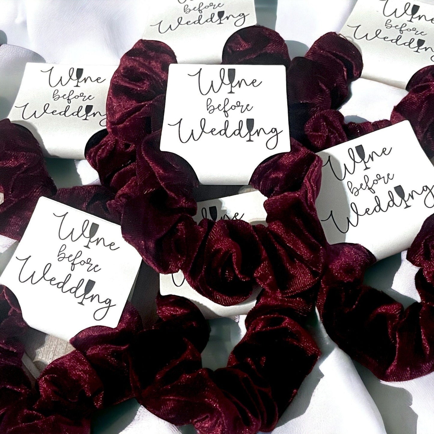 Burgundy scrunchies with 'Wine before Wedding' cards on a white background