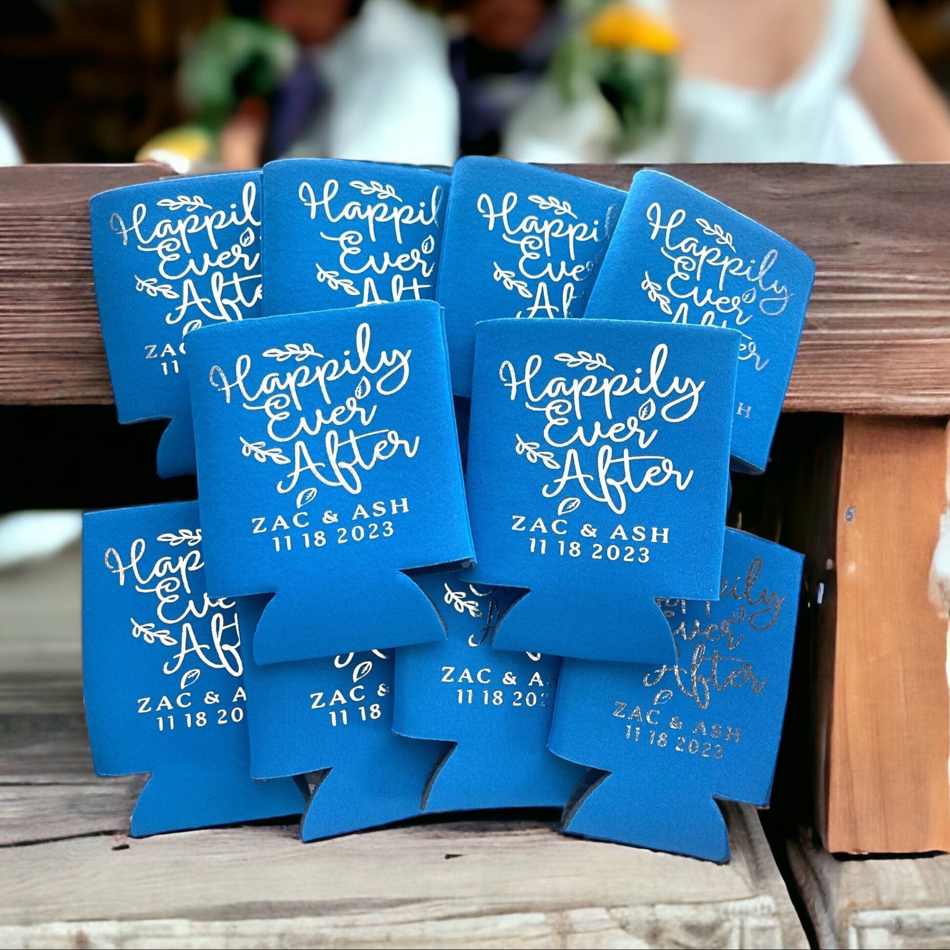 Blue can coolers with 'Happily Ever After' text on a wooden surface.