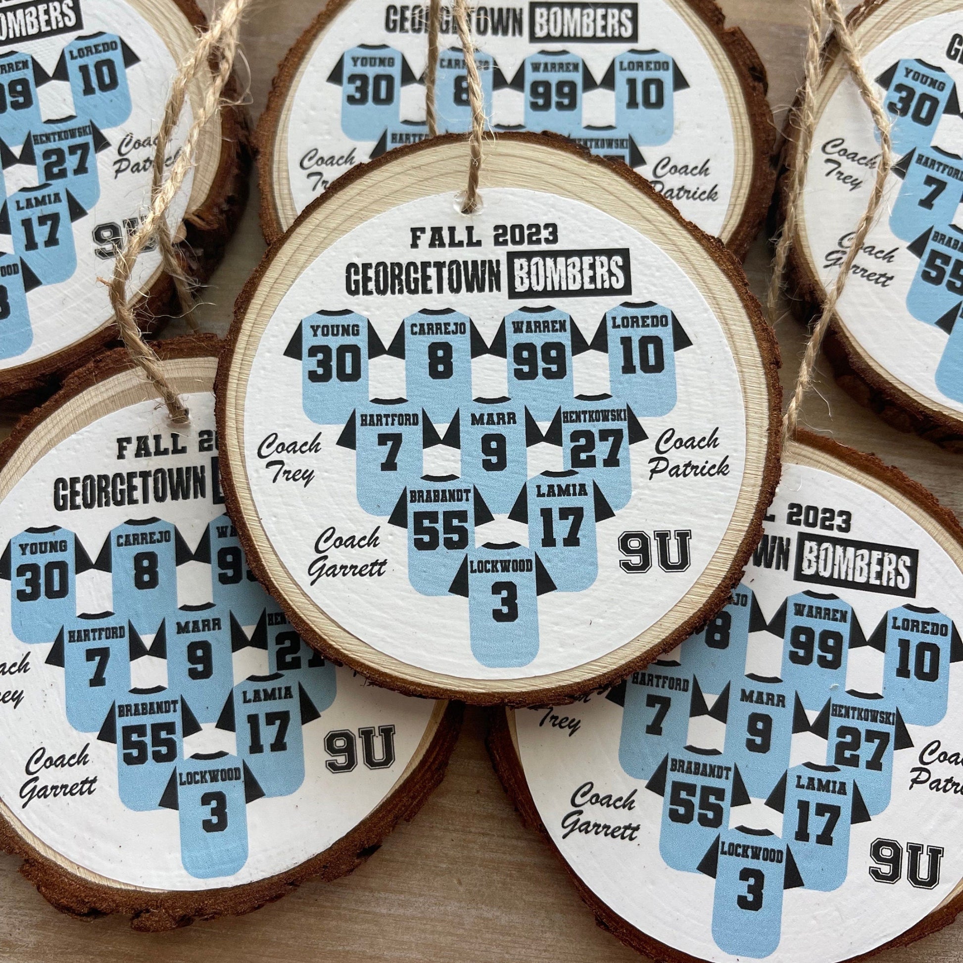 Wooden ornaments with sports team designs and player numbers on a wooden surface.
