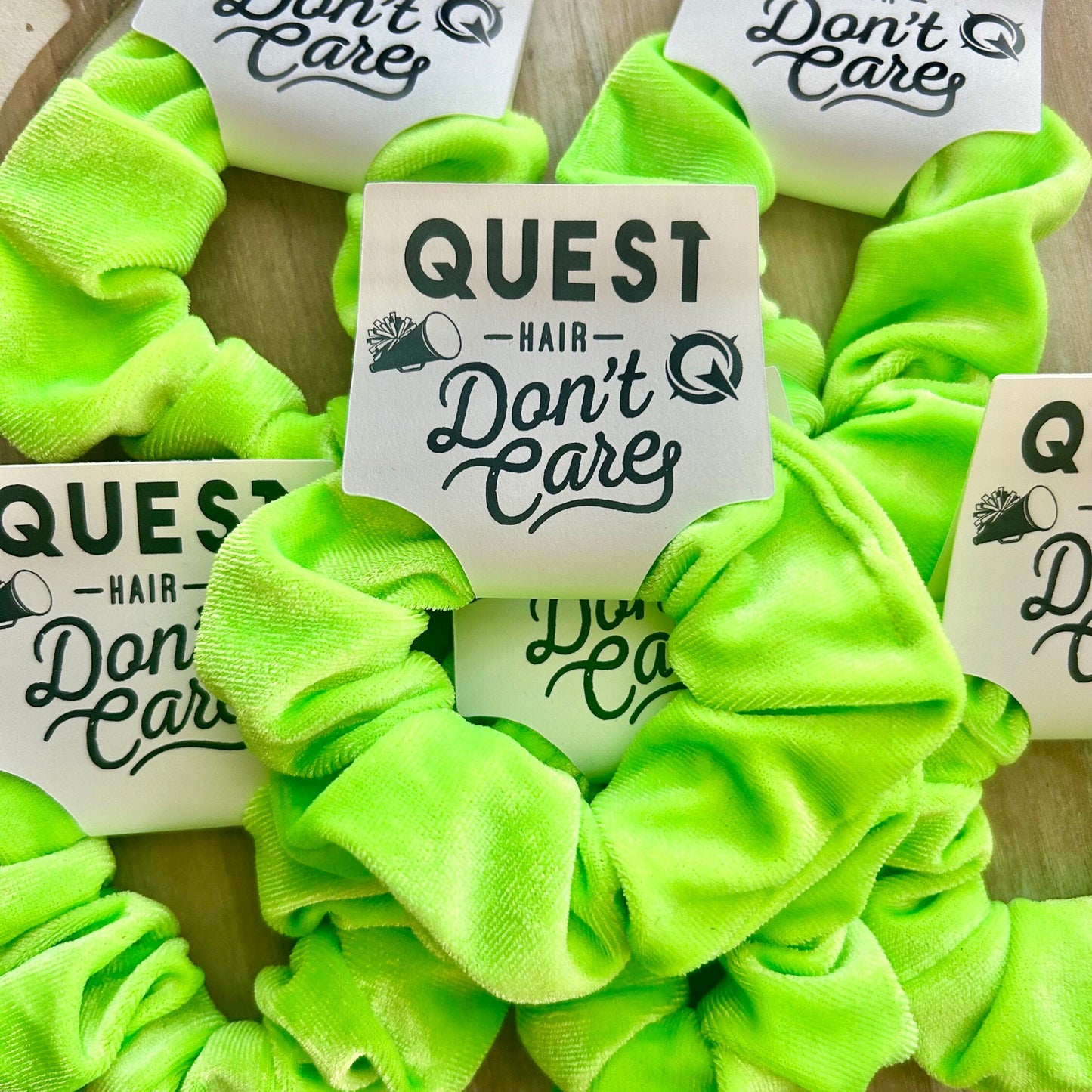 Neon green scrunchies with 'Quest Hair Don't Care' labels on a textured surface
