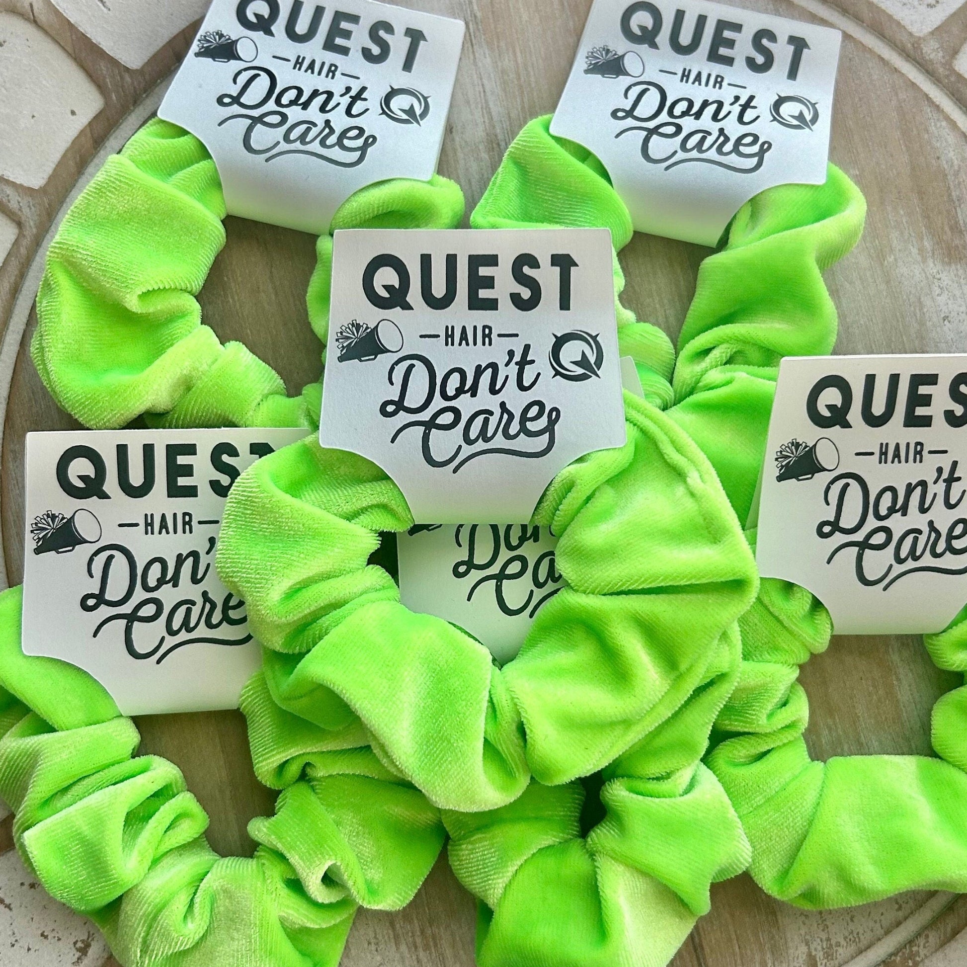 Neon green scrunchies with 'Quest Hair Don't Care' labels on a textured surface