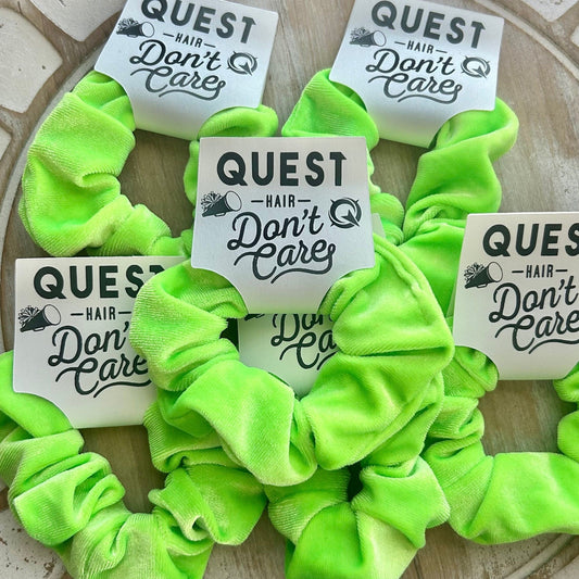 Neon green scrunchies with 'Quest Hair Don't Care' labels on a textured surface