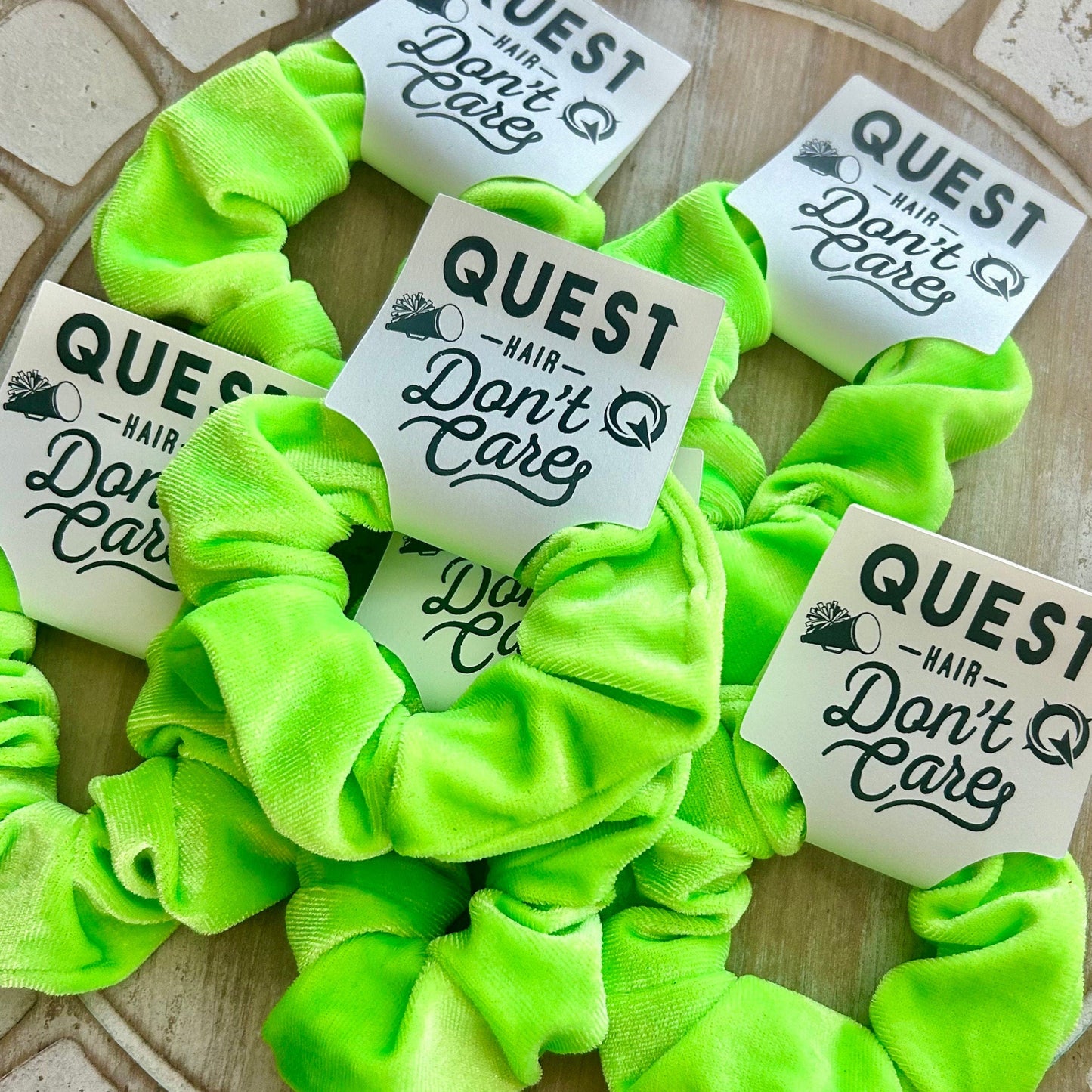 Neon green scrunchies with 'Quest Don't Care' labels on a textured surface
