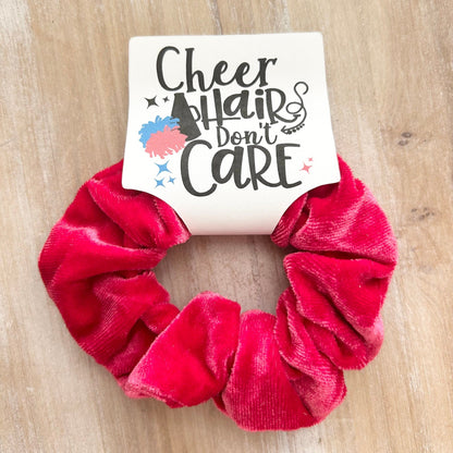 Pink scrunchie with a sign that says 'Cheer Hair Don't Care' on a wooden surface