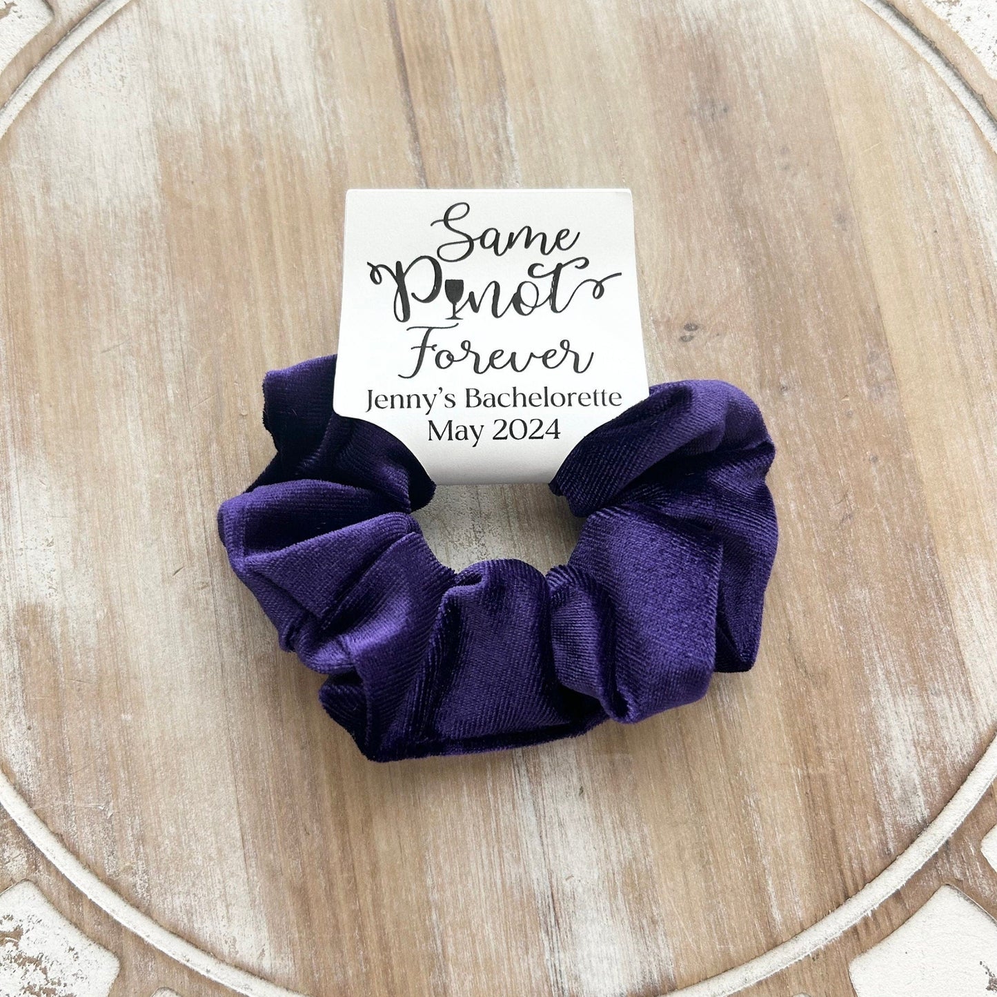 Purple scrunchie with a card on a wooden surface