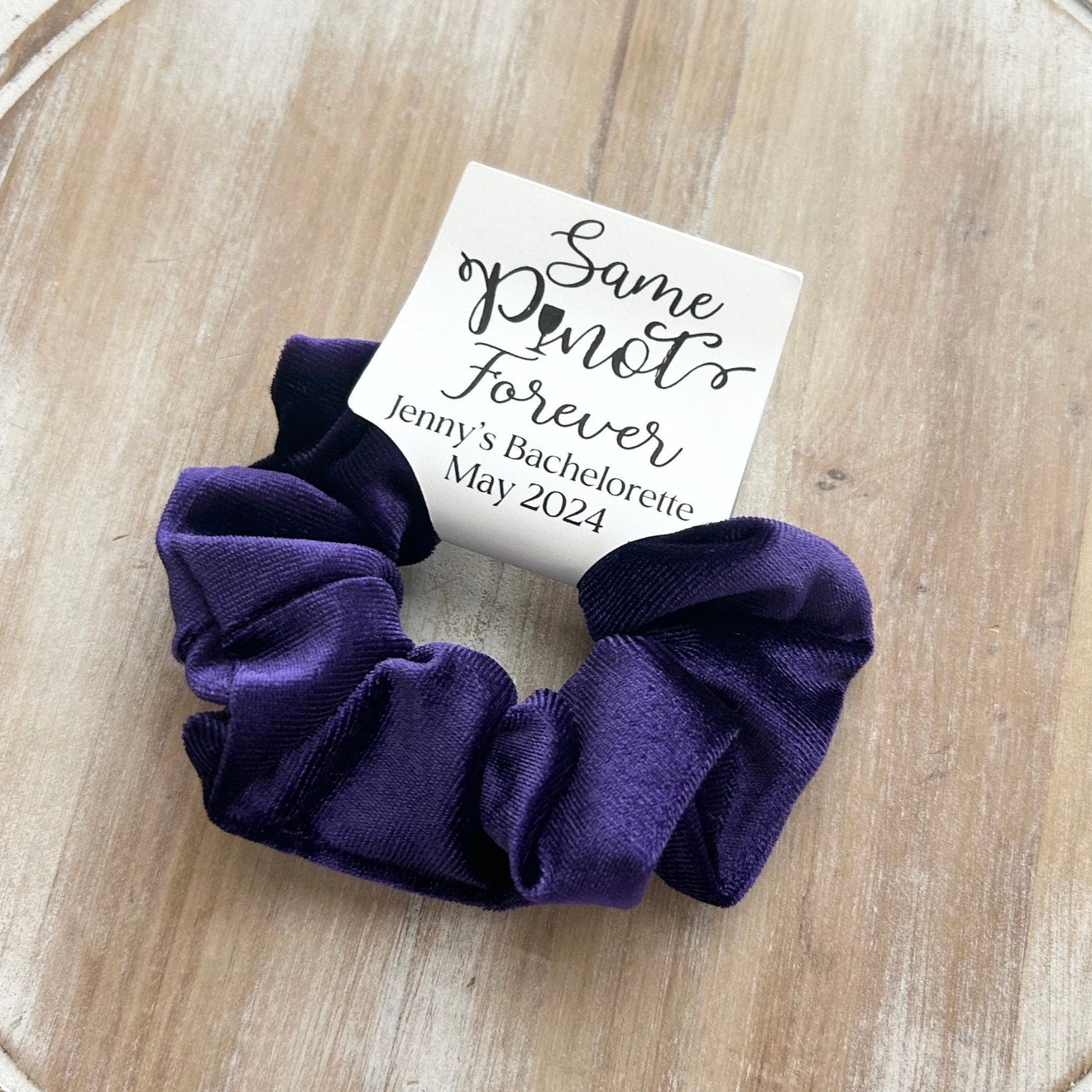 Purple scrunchie on a wooden surface with a card labeled 'Same Pointe Forever'.