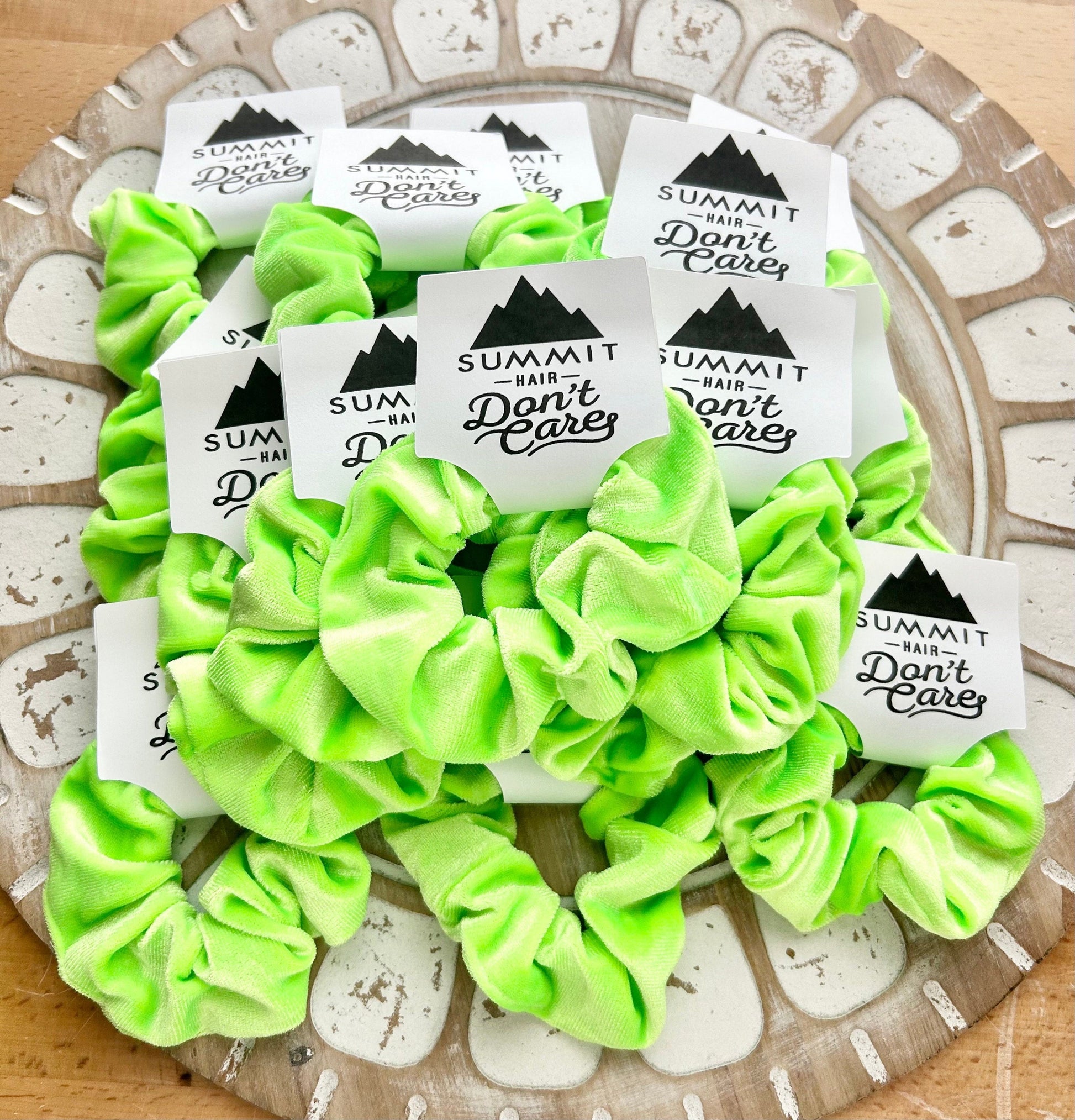 Green scrunchies with 'Summit Hair Don't Care' labels on a decorative plate.