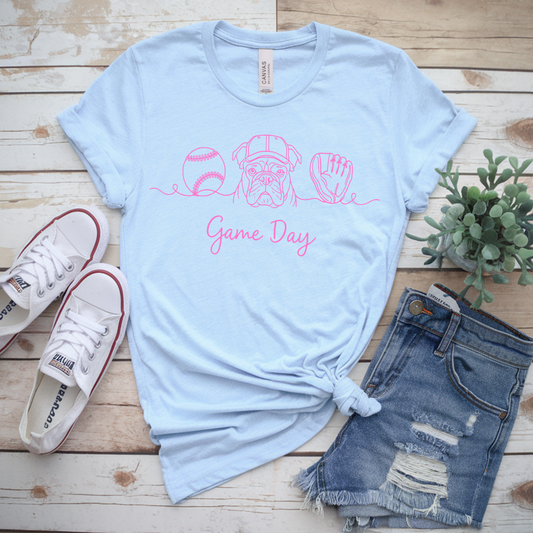 Light blue t-shirt with 'Game Day' and sports graphics, paired with denim shorts and sneakers on a wooden surface.