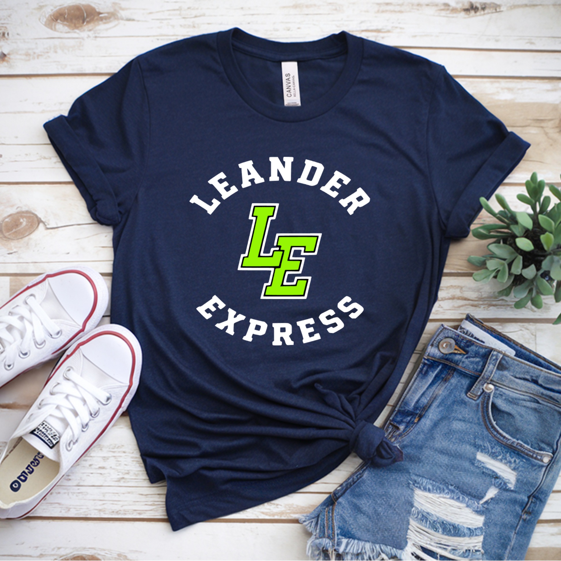 Navy blue t-shirt with 'Leander Express' print on a wooden surface with sneakers and jeans.