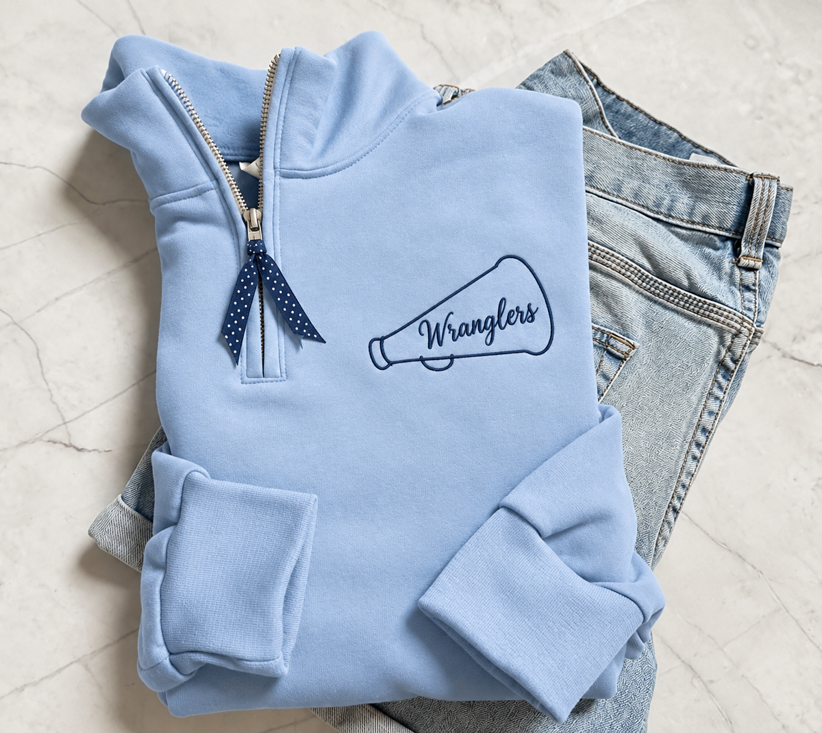 Powder blue Wranglers quarter-zip with navy embroidered megaphone and polka-dot ribbon zipper pull
