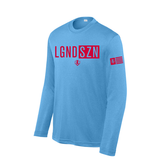A light blue long-sleeve t-shirt with 'LGND SZN' printed in red across the chest, a small red emblem below it, and a red flag patch on the right sleeve, shown on a plain white background.