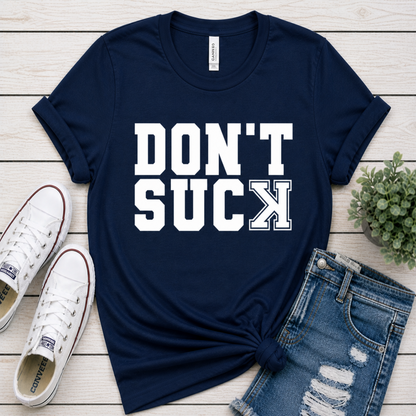 Navy blue t-shirt with 'DON'T SUCK' text, white sneakers, and denim shorts on a wooden surface.
