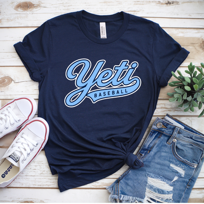 Navy blue t-shirt with 'Yeti Baseball' text, white sneakers, and denim shorts on a wooden surface.