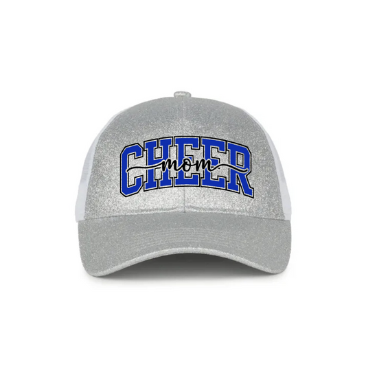 A silver glitter trucker hat with white mesh side panels and a curved brim. The front features the text 'CHEER mom' in blue varsity-style lettering with a black script overlay.