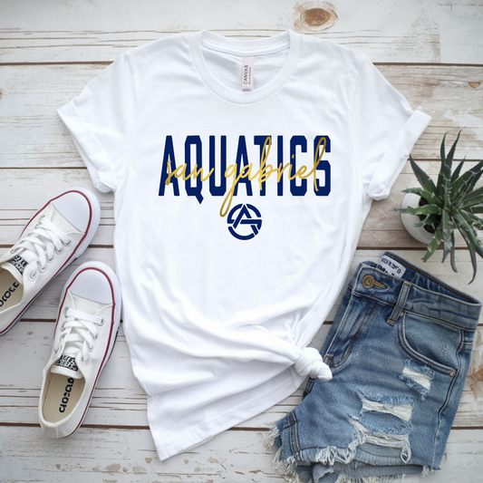 White t-shirt with 'Aquatics' text, white sneakers, denim shorts, and a plant on a wooden surface.
