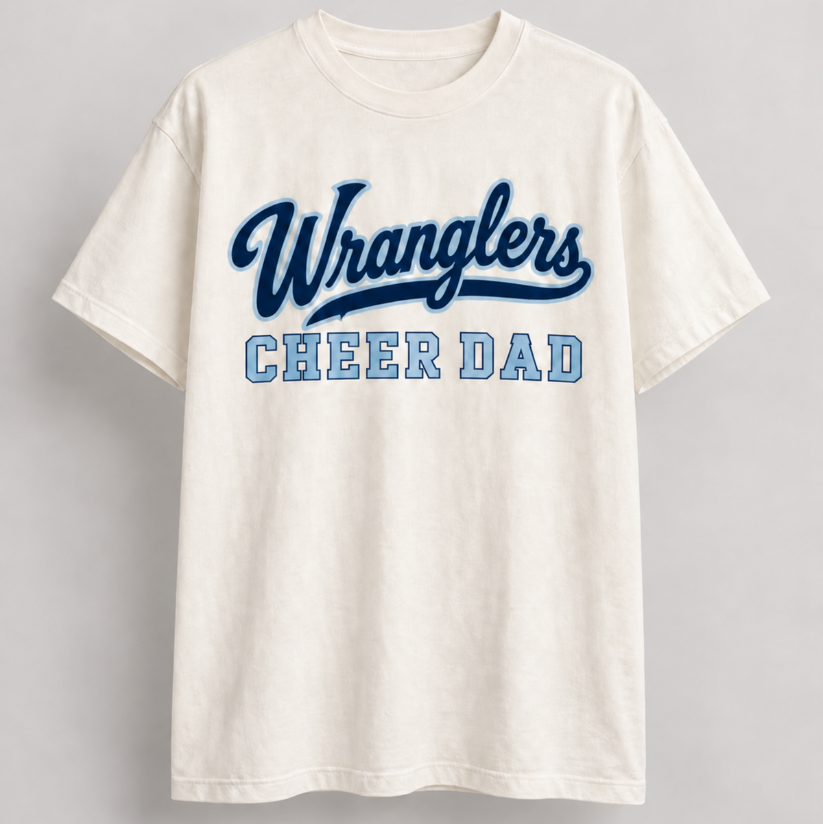 An off-white crewneck t-shirt featuring 'Wranglers' in dark blue script and 'CHEER DAD' in light blue block letters across the chest, displayed against a neutral gray background.