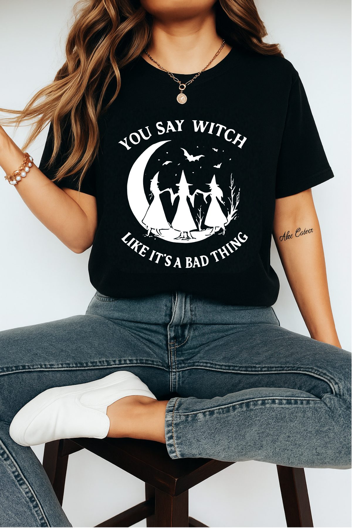 Woman wearing black witchy graphic tee with moon and witch design — spooky season outfit.